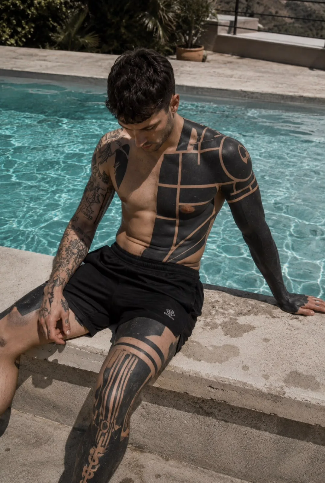 Composición geométrica de blackwork sobre torso, brazo y pierna