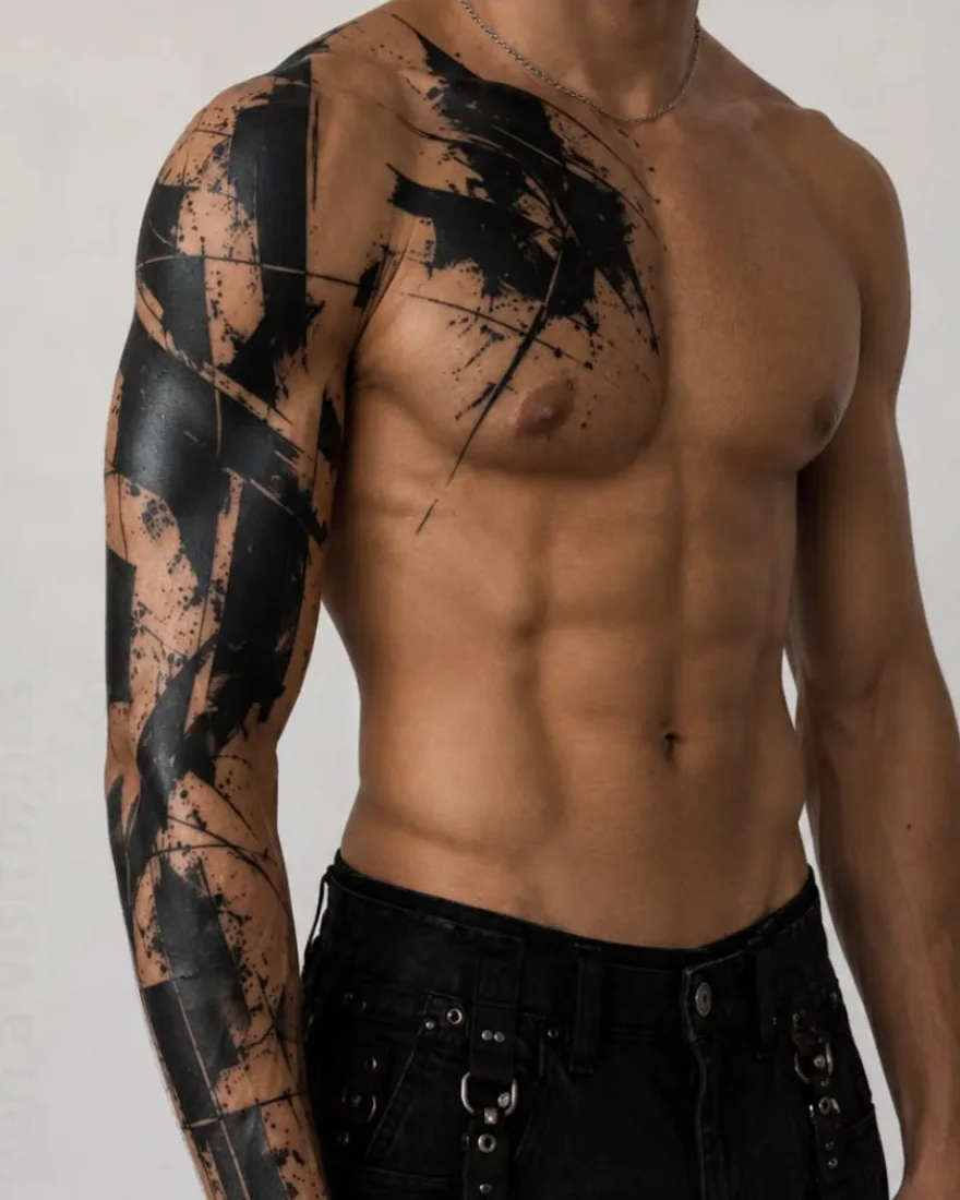 Tatuaje blackwork de pinceladas sobre brazo y hombro