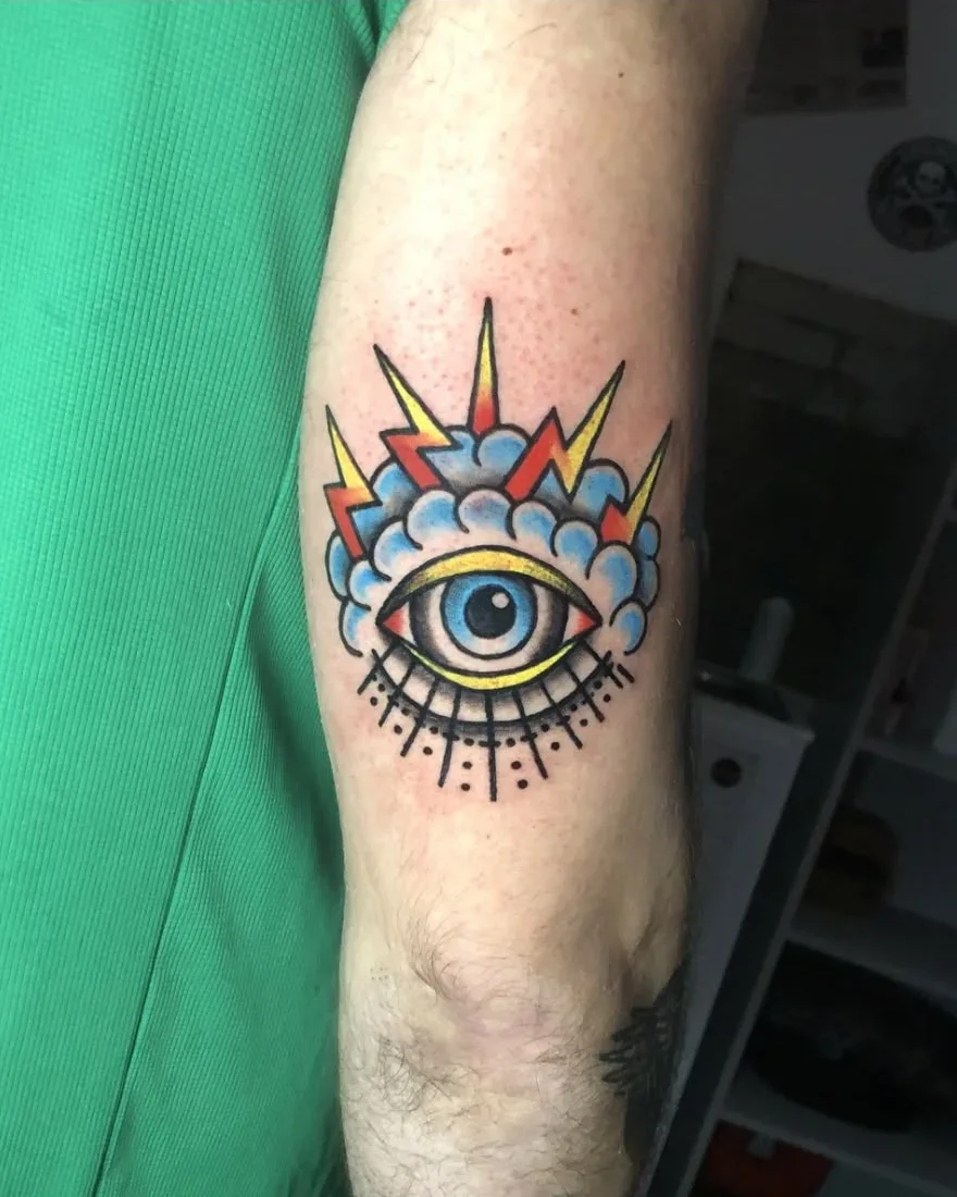 Tatuaje a color de un ojo entre nubes y rayos
